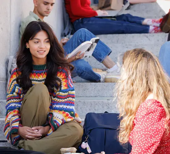 Students in colorful clothing sitting and talking on the steps of Low Library.