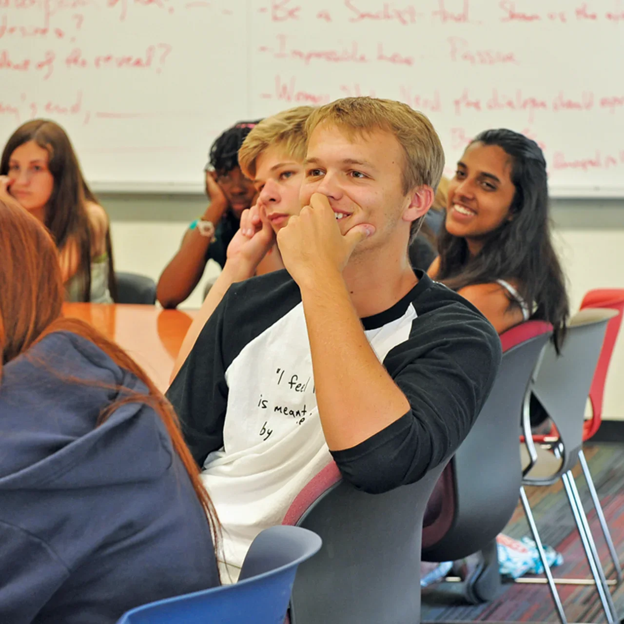Students smiling and listening in a classroom.