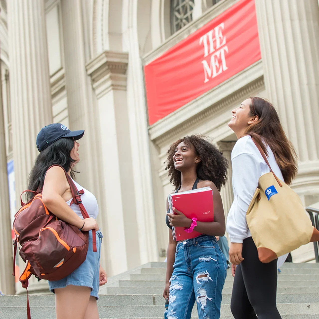 Three students laugh outside of The Met.