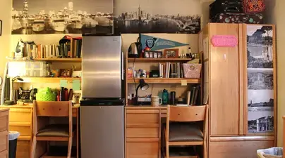 A furnished student room in Schapiro with two desks, refrigerators, and cabinets.