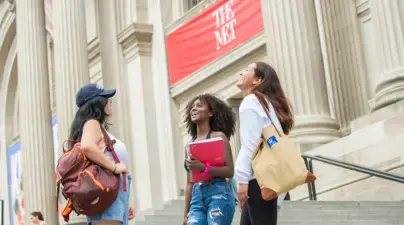 Three students laugh outside of The Met.