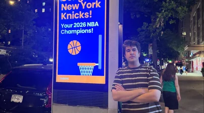 Yigit next to a board promoting the Knicks